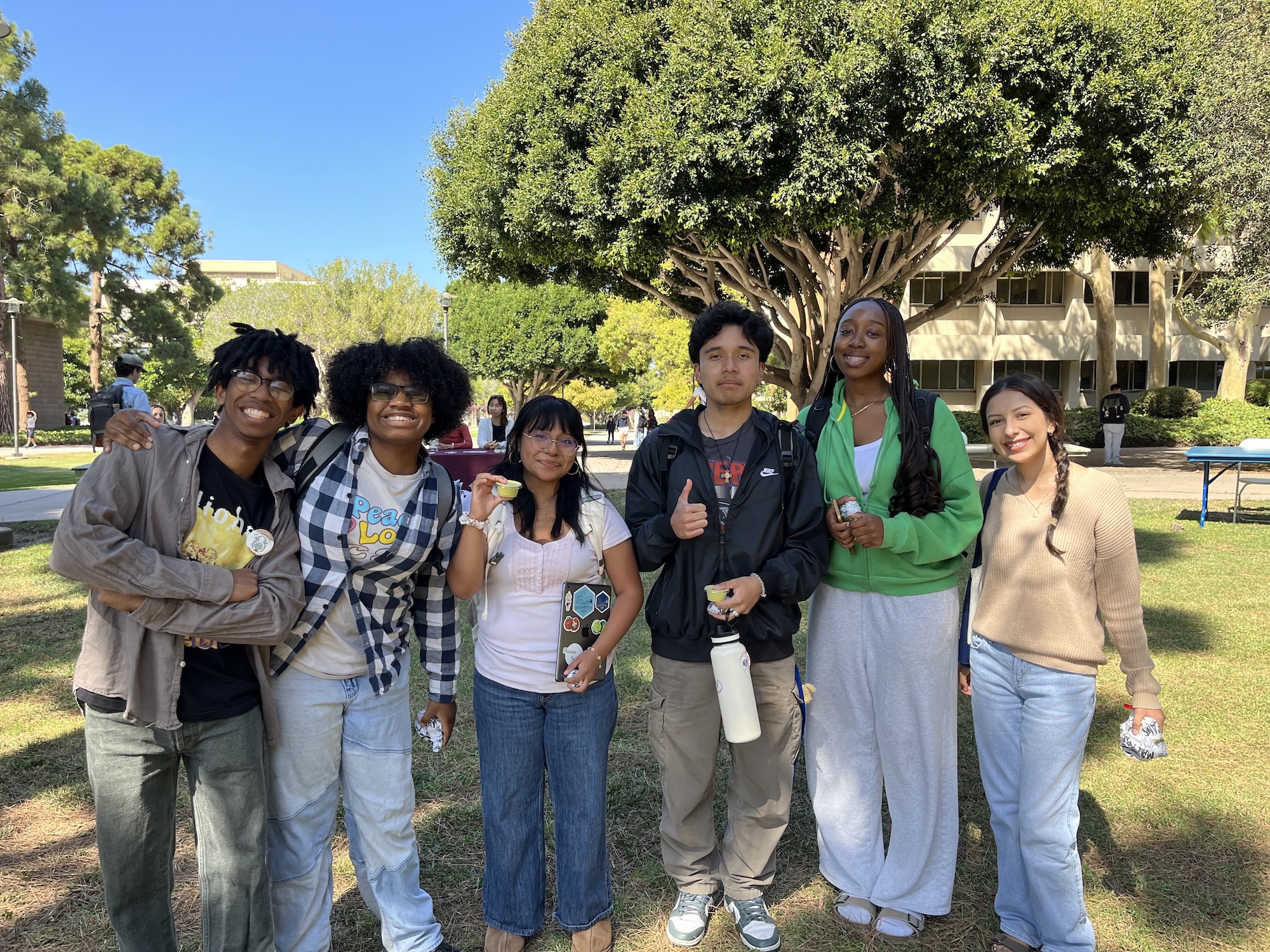 Six college students standing in a line outside smiling.
